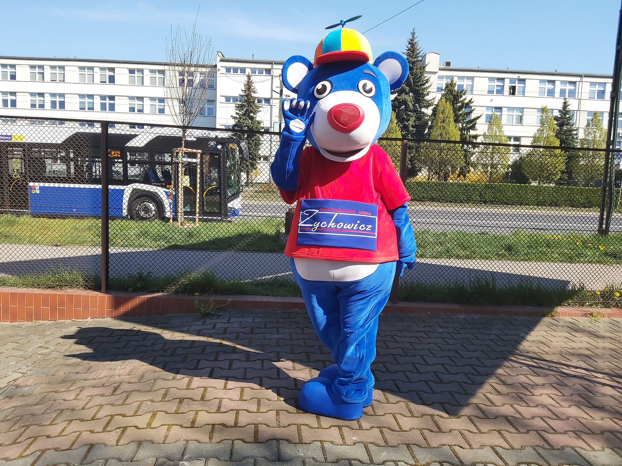Na fotografii widnieje przebranie inspirowane wizją postaci niebieskiego miśka pozujące do zdjęcia przed siedzibą firmy Elabika